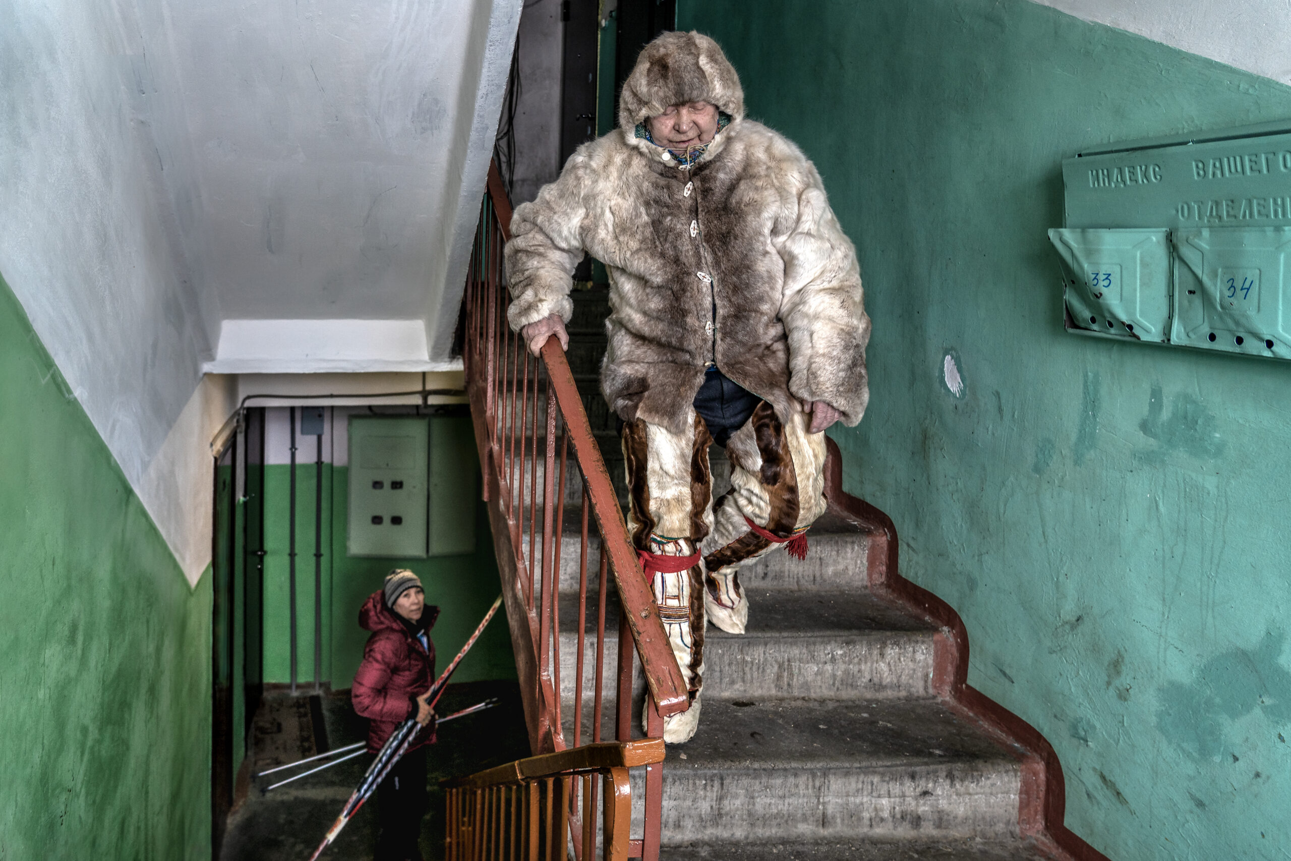 Piotr Galkin is a saami reindeer herder from father to son. // A reindeer herder from father to son, Piotr Galkin is Uliana's grand-father. Dressed in a traditional reindeer skin outfit, he descends the stairs of his building to go to Prazdnik Severa (“the festival of the North”) which takes place every year at the end of March. For a long time, he participated in reindeer driving competitions, but at the height of his 93 years, his health no longer allows him to drive. He is one of the last hereditary reindeer herders of the Saami ethnic group in Russia.